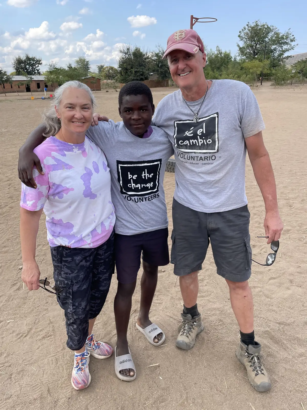 A BTCV Kid in a Be The Change T-shirt with two BTCV volunteers in a schoolyard