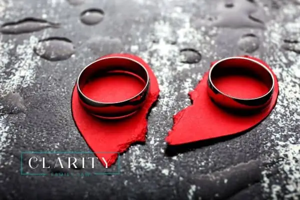 a torn paper heart with two wedding rings on top of it