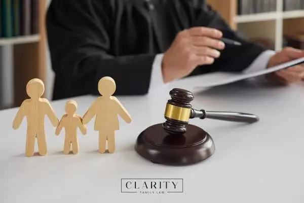 Wooden family figures, a judge's gavel, and a hand holding papers.