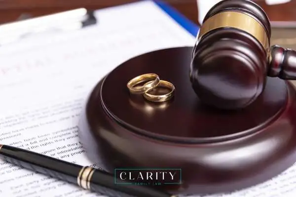 a gavel, wedding rings, and prenup on a desk