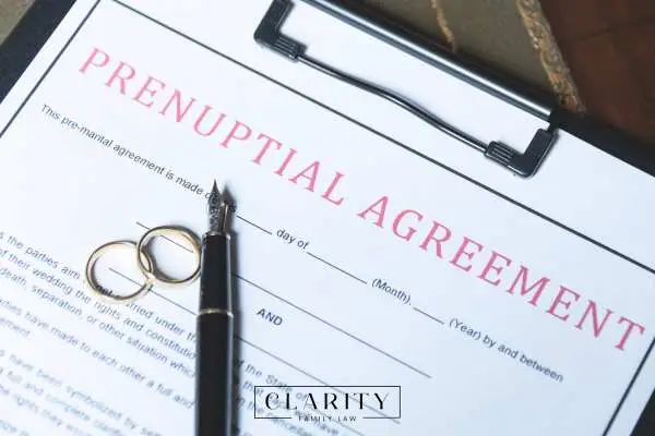 a prenup on a clipboard with a pen and wedding rings