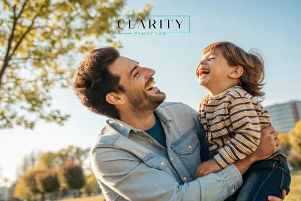 A man and a young child laughing together outdoors
