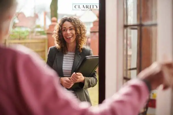 Woman opening front door for social worker in a grey suit