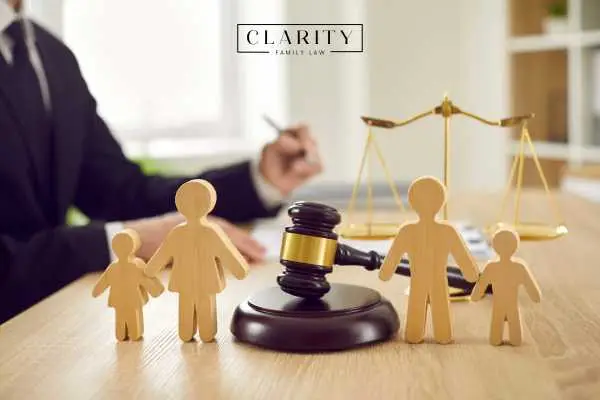 a cut out of a family and a gavel on a desk while a lawyer looks over a custody order in the background