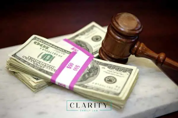 A wooden judge’s gavel resting on two large bundles of 100-dollar bills.
