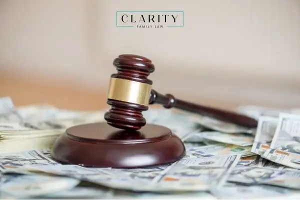 A wooden judge’s gavel sitting on a scattered pile of 100-dollar bills.