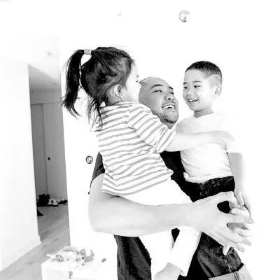 Black and white photo of man carrying two children
