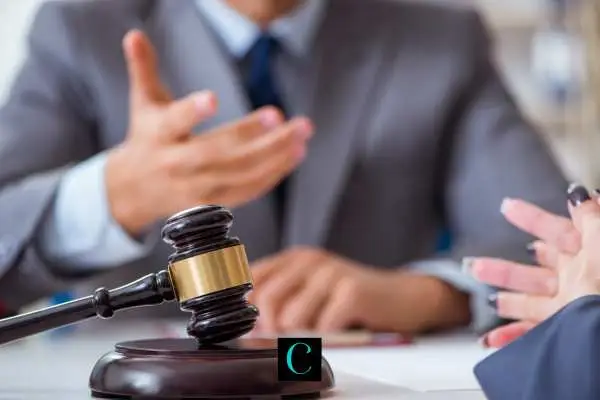 A judge's gavel with a blurred lawyer in the background.