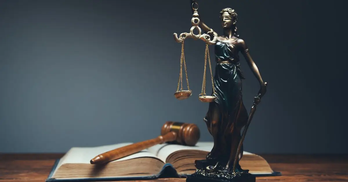 Lady Justice in front of an open book with a mallet resting on it
