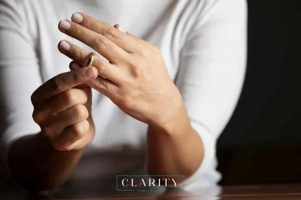 A close-up of a person removing a gold wedding band from their ring finger.