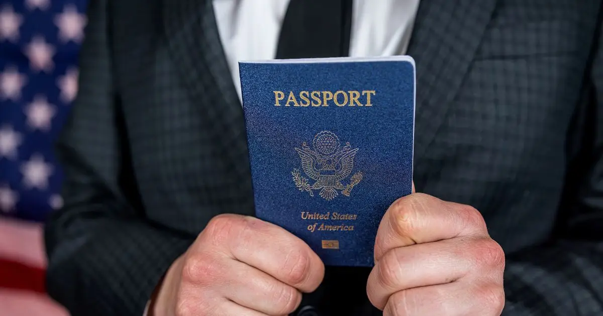 man in suit holding a US passport in both hands