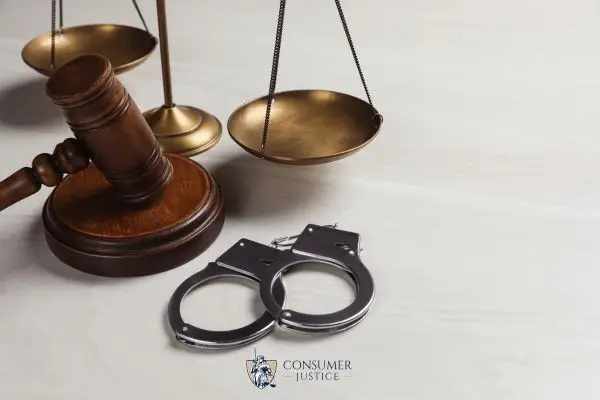 handcuffs, a a gavel, and scales on a white desk