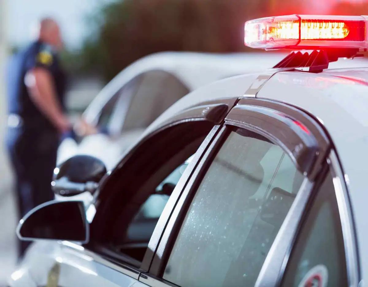 a police officer approaching a car after pulling a driver over