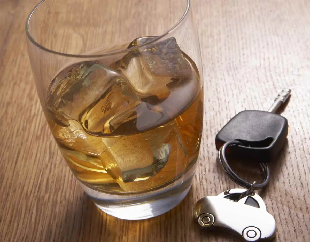 a car key and glass of alcohol on a table