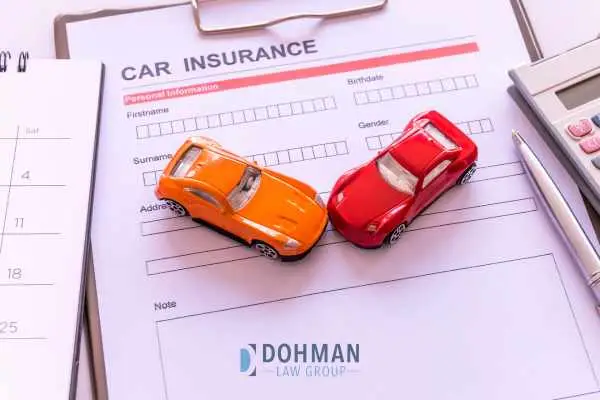 a car insurance application form and two model cars on a desk