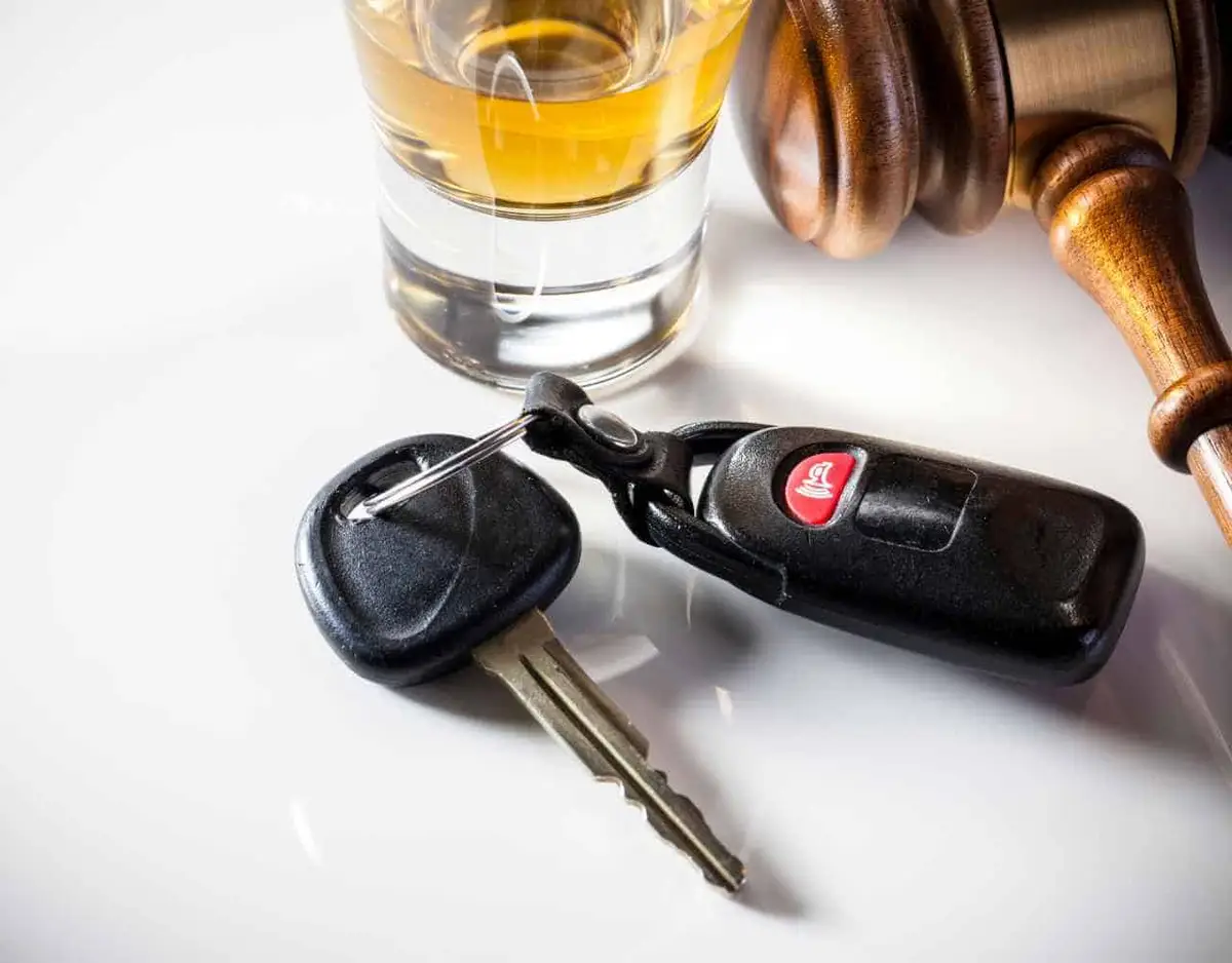 car keys, alcohol, and a gavel on a white table