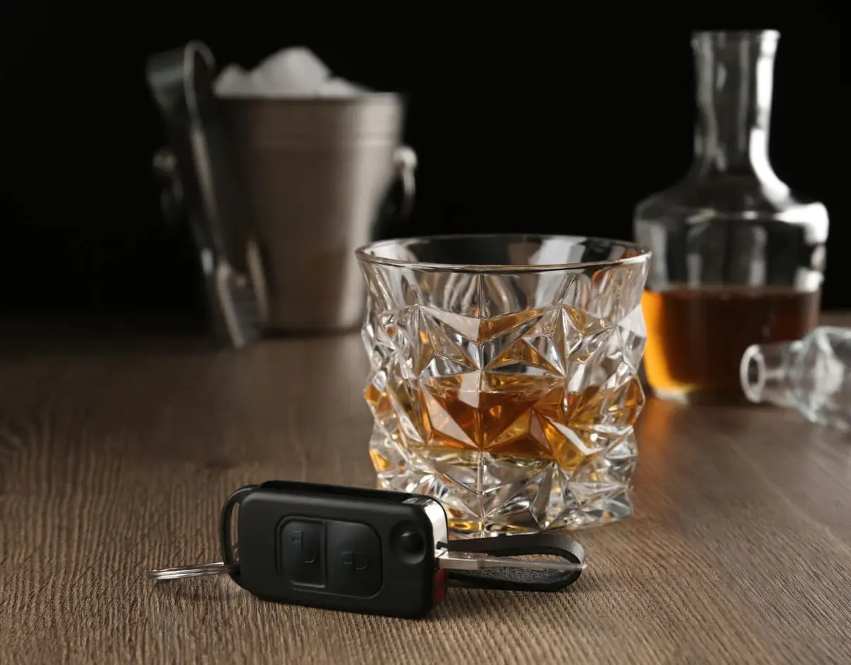 Car keys in front of a glass of whiskey.