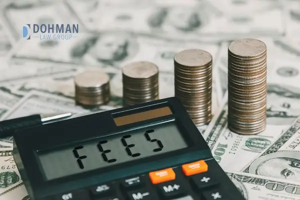 A calculator with the word FEES on the display over a pile of cash and stacks of coins.