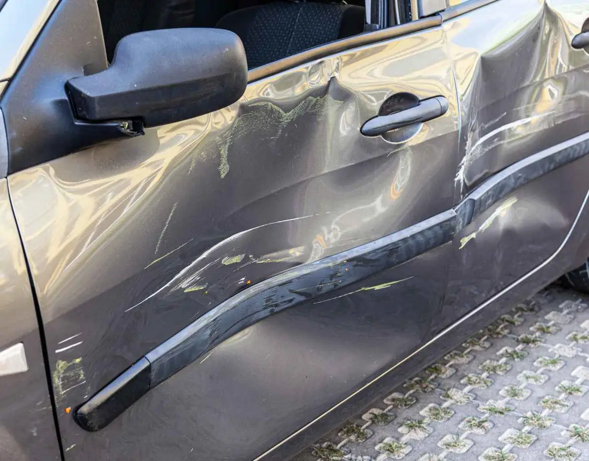 a car with damage to its driver's side after a hit and run