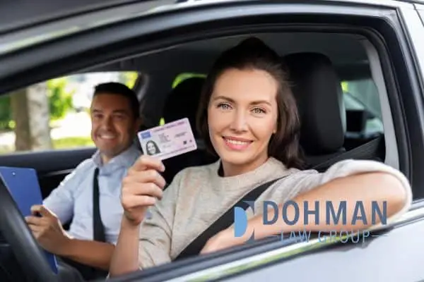 A woman in a car holding up her driver's license