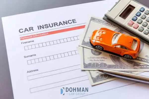 a calculator, money, model car, and insurance forms on a table