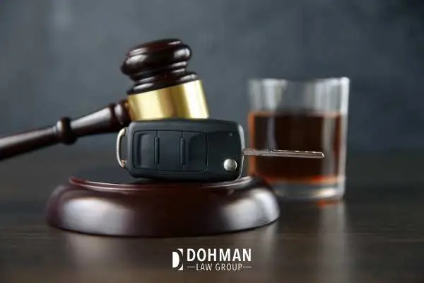 a glass of whiskey, keys, and a gavel on a desk