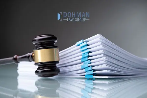 A gavel resting next to a large, thick stack of legal documents held together by blue binder clips.