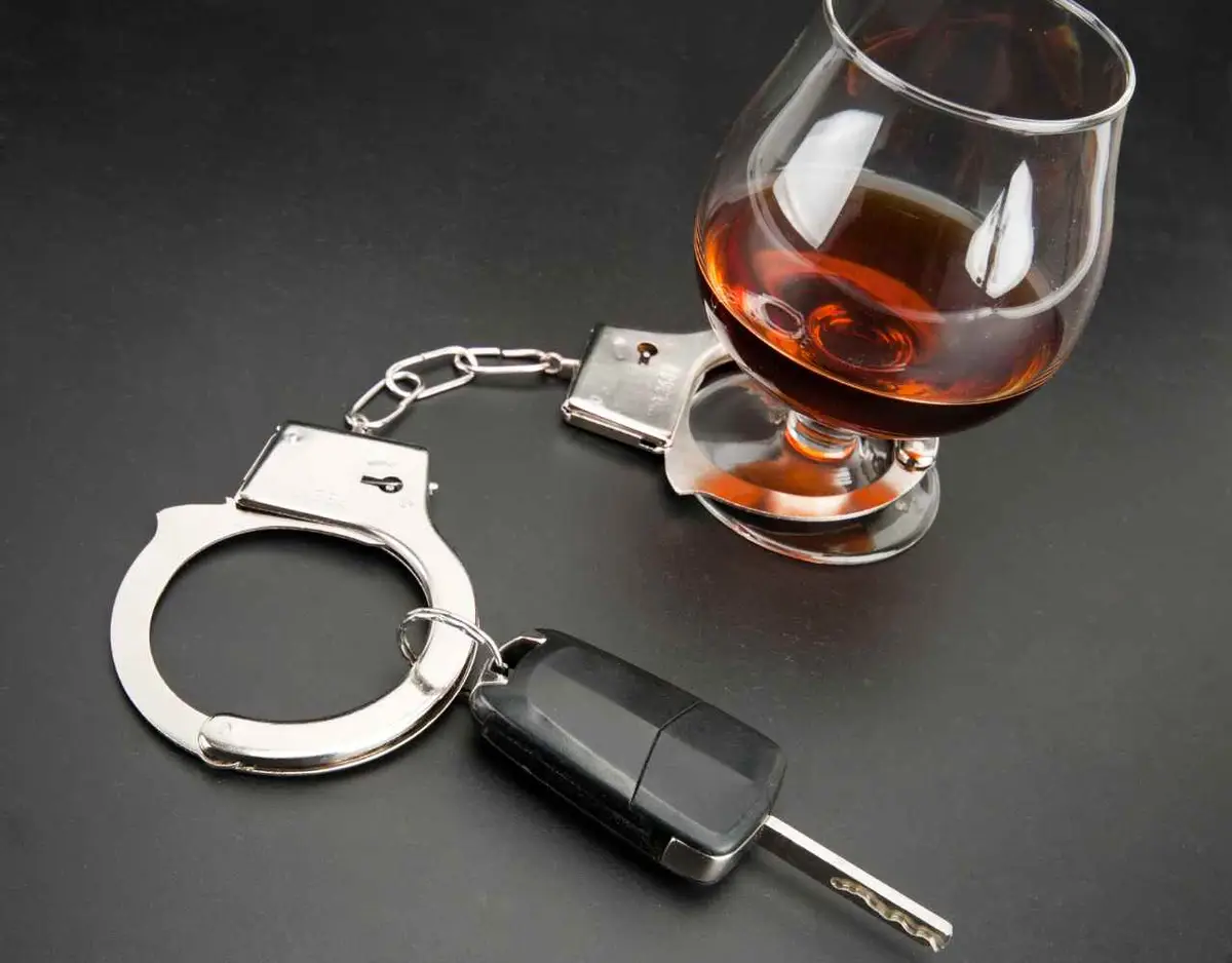 handcuffs, a car key, and tumbler of alcohol sitting on table