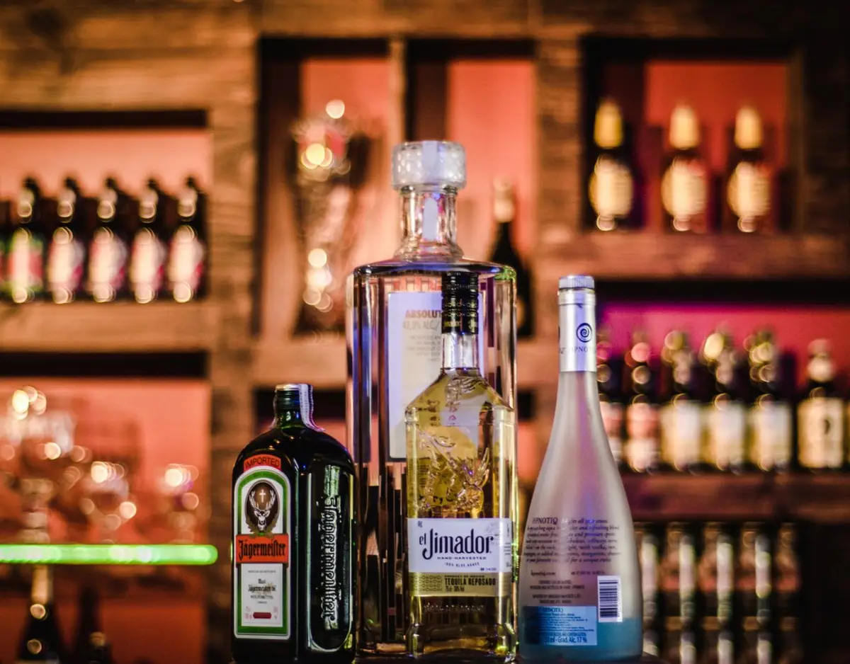 several liquor bottles on a bar, with the background out of focus.