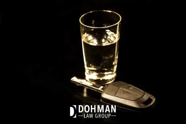 a shot glass and car key on a black backdrop