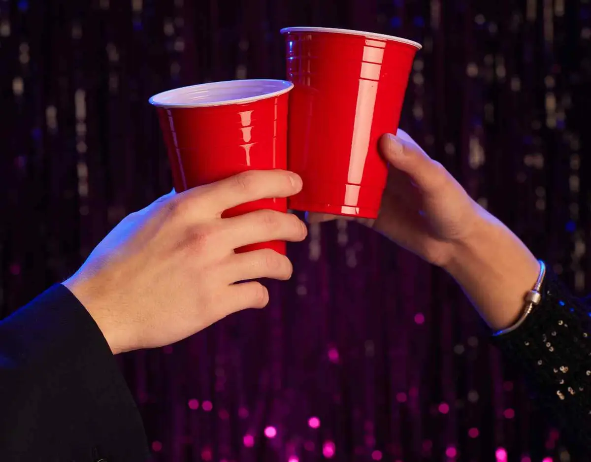 2 people toasting with red solo cups