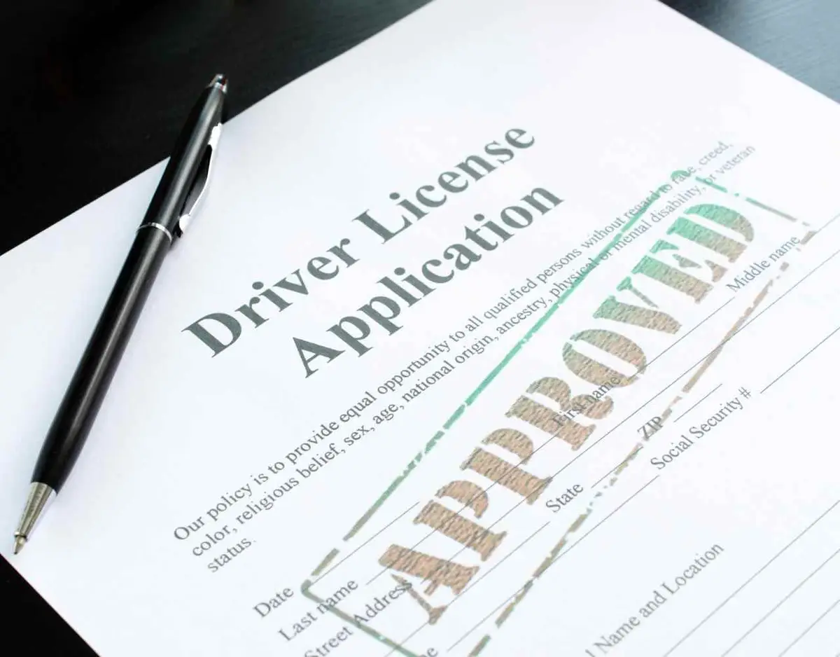 an approved drivers license application and a pen on a desk