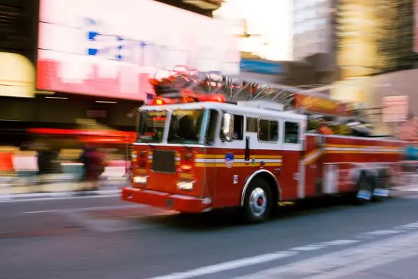 red fire truck moving quickly down a blurred city street.