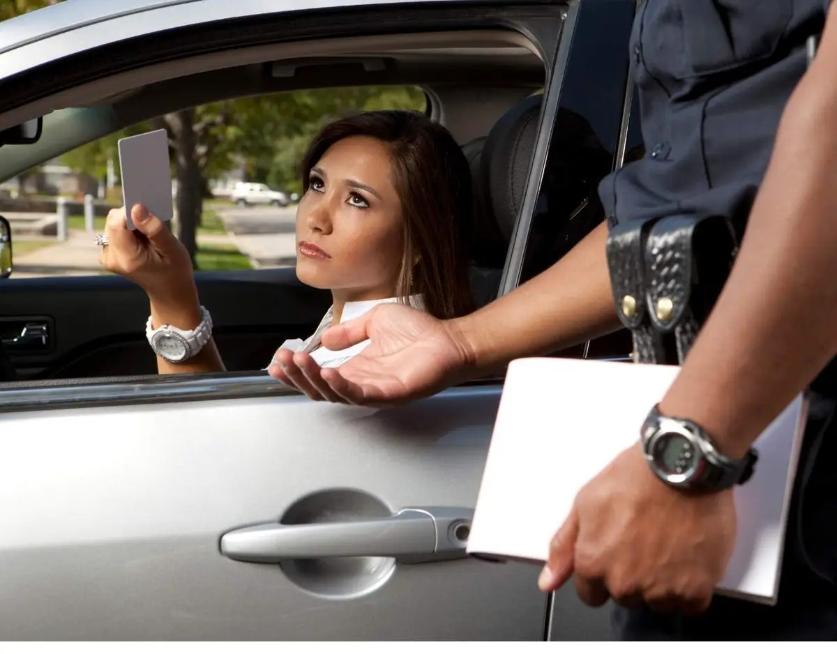 Analysis Police officer leaning in, speaking to a woman in a car who is holding her driver's license