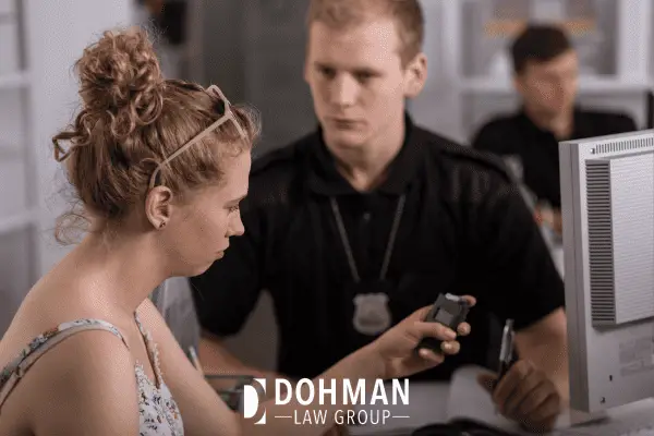 Woman in a police station taking a breathalyzer for a DUI