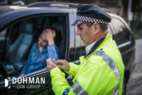 A police officer is speaking to a distressed driver in a car.