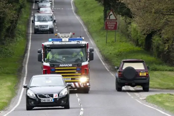 A fire truck on a two-lane road with other vehicles yielding