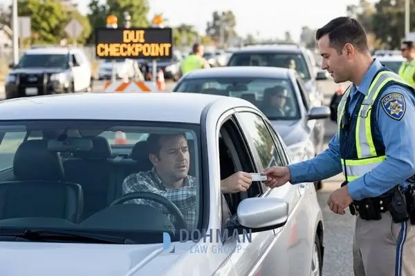 A police officer taking a driver's license from a motorist at a nighttime DUI checkpoint.
