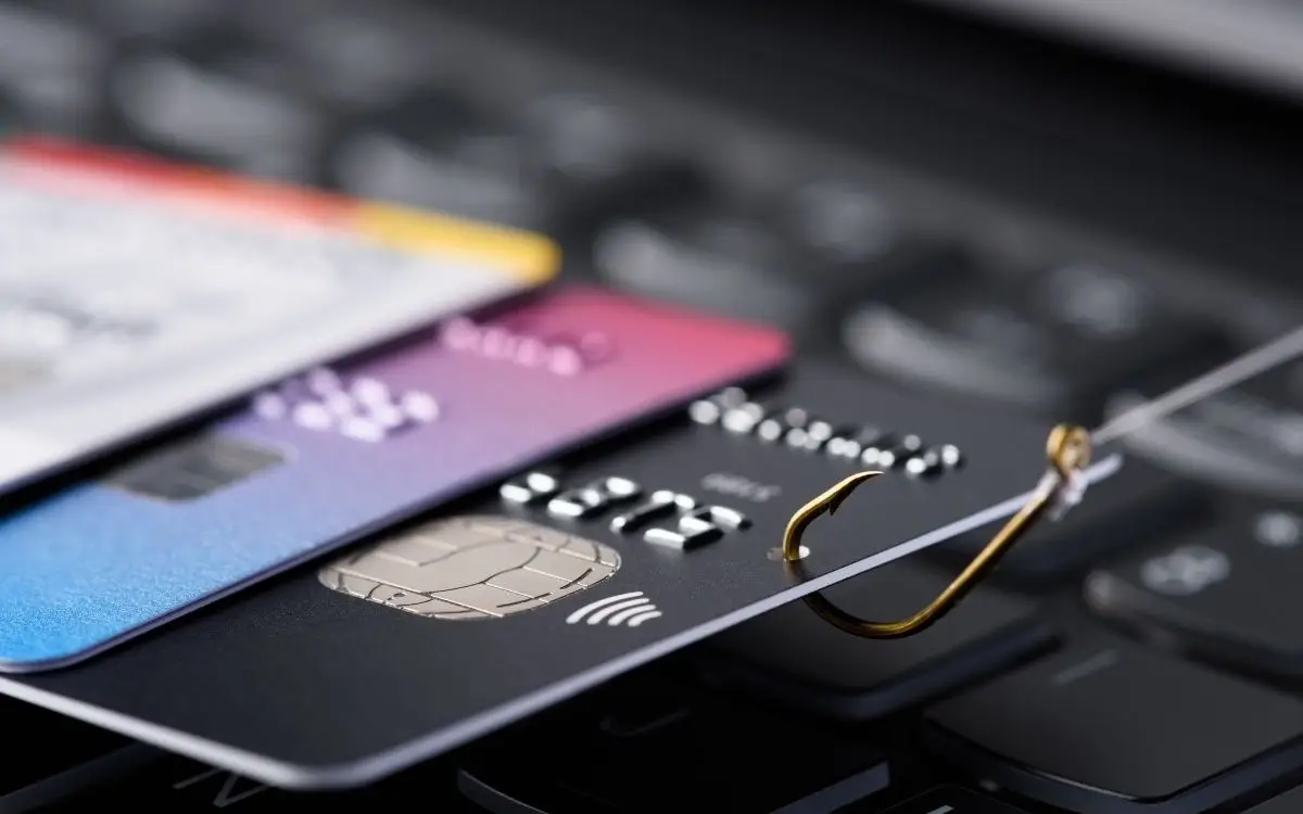 Credit cards on a laptop keyboard with a fishing hook hooked into one.