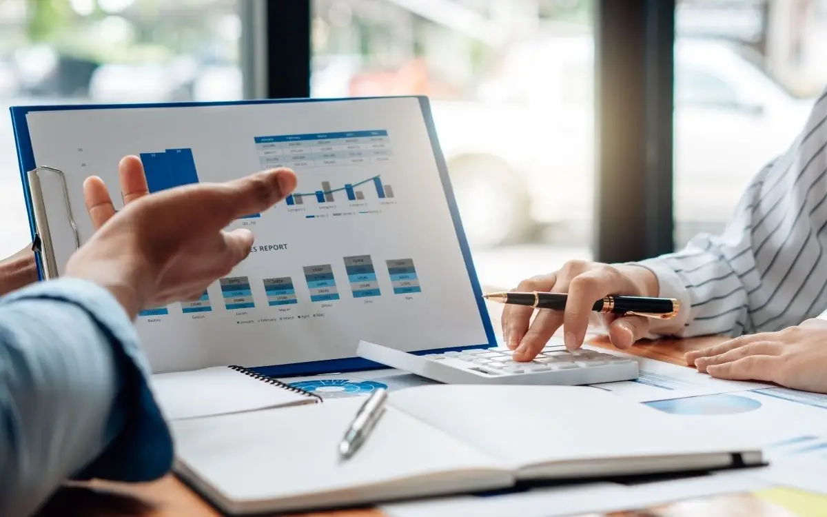 close-up of two people reviewing financial charts on a clipboard.