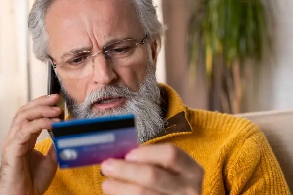 a man holding his credit card while on the phone trying to understand his credit report