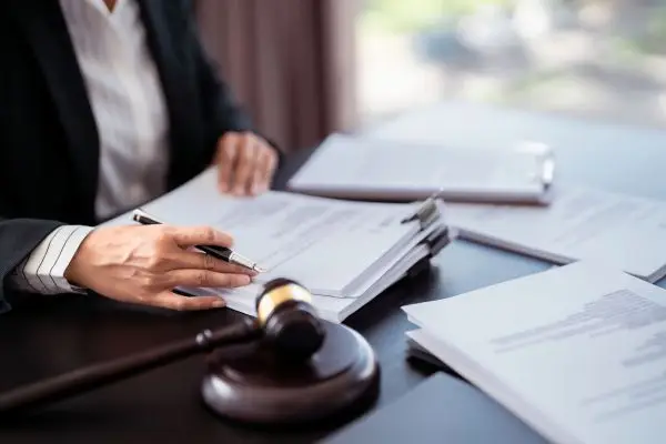 A person's hands are on legal documents with a gavel nearby, suggesting a legal professional at work.