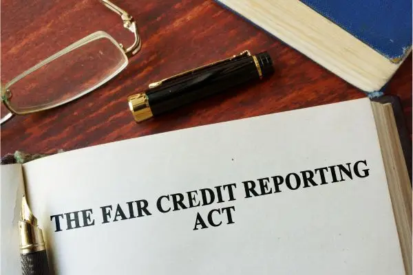 book with fair credit reporting act with pen, glasses, and book around it