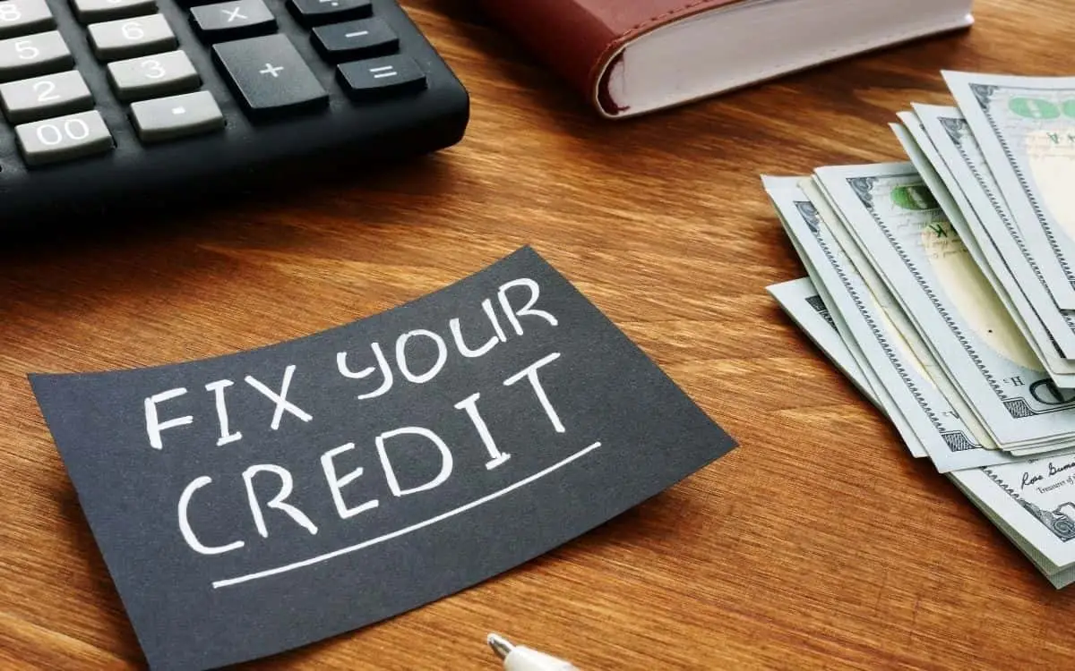 black card with white writing saying fix your credit with cash and a calculator around it