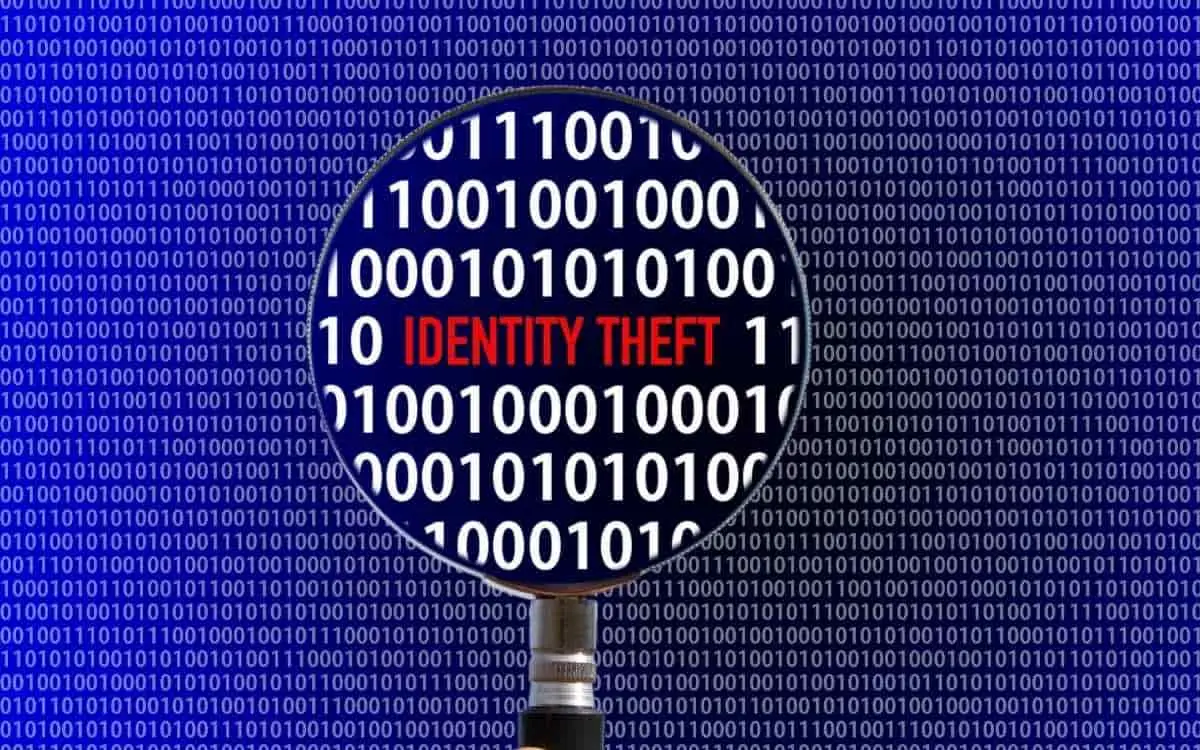 A magnifying glass over a background of binary code, highlighting the words "IDENTITY THEFT"