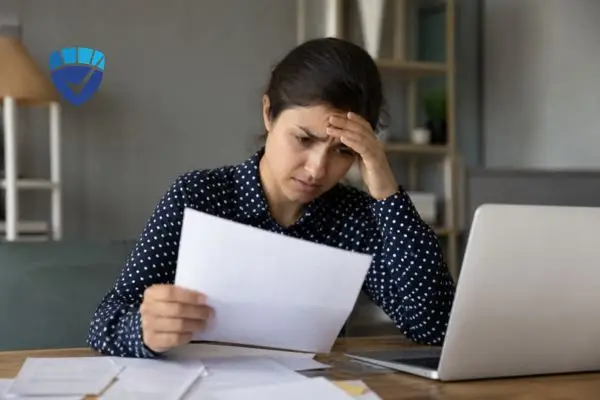 Frustrated woman reviewing credit report documents at her laptop