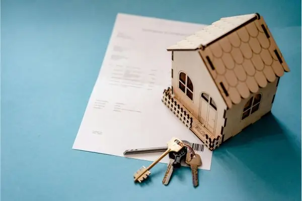 paper with wooden house on top and house keys