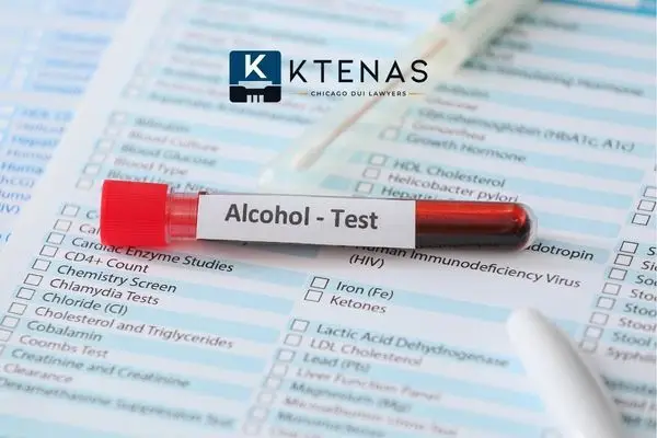 A blood sample vial labeled "Alcohol - Test" resting on top of a medical lab requisition form