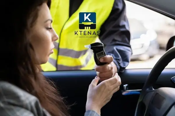 Police conducting a breathalyzer test to a women in her car.