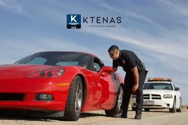 A police officer leaning into the window of a red sports car during a traffic stop